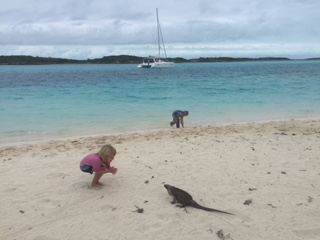 Karen (4) with n Bahamian Rock Iguana. Henry (4) and our catamaran, SV Aphrodite, in the background.