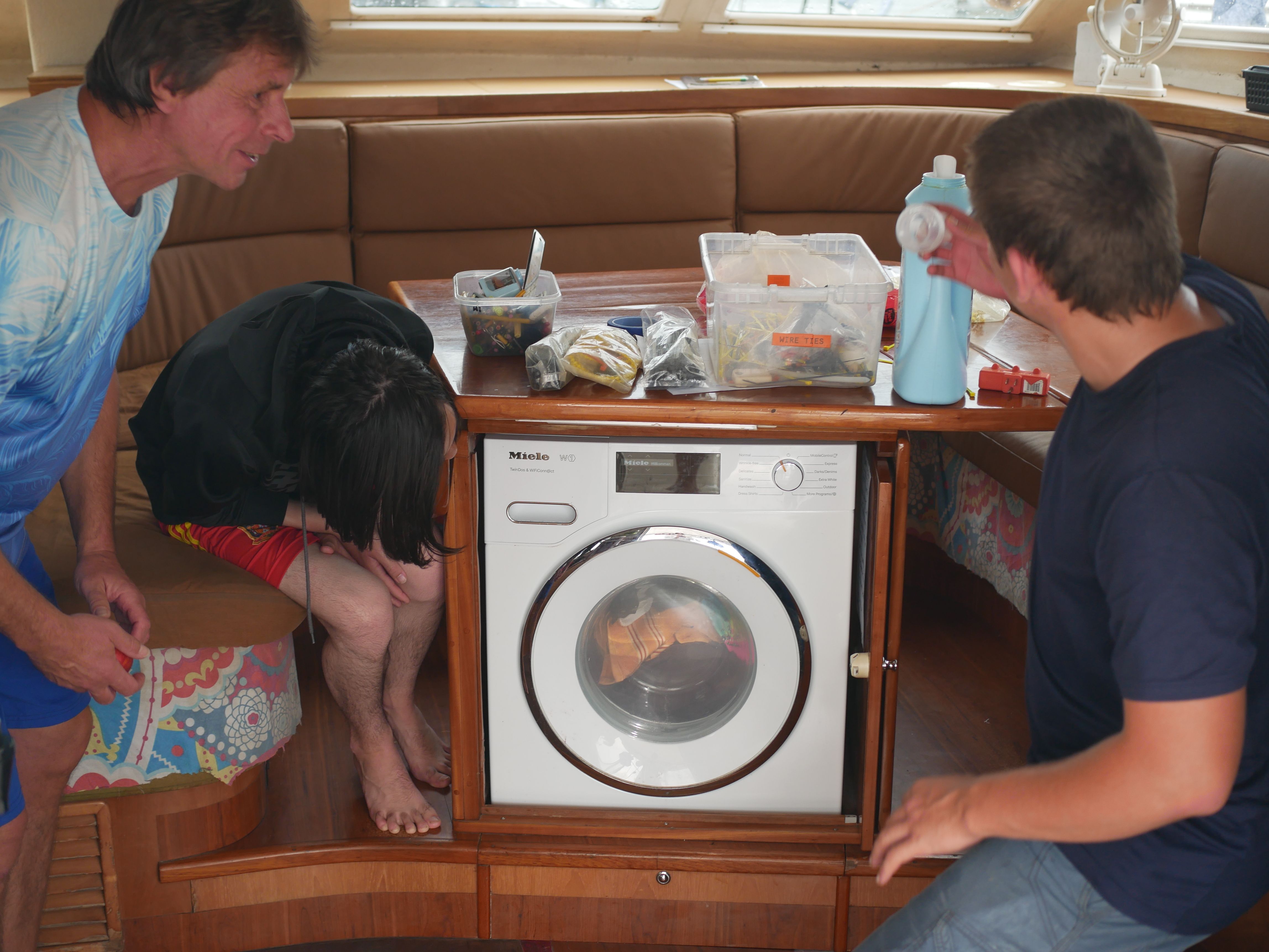 Extended Escher family on SV Aphrodite enjoy the wonders of the Miele W1 washine machine below the saloon table.