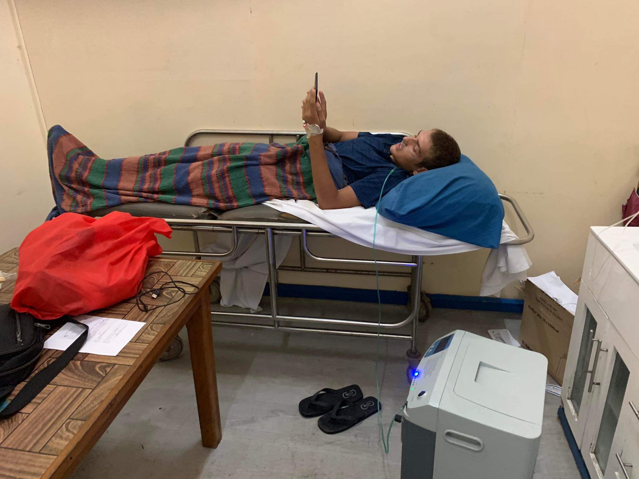 Paul in a hospital bed reading his Kindle while receiving oxygen therapy