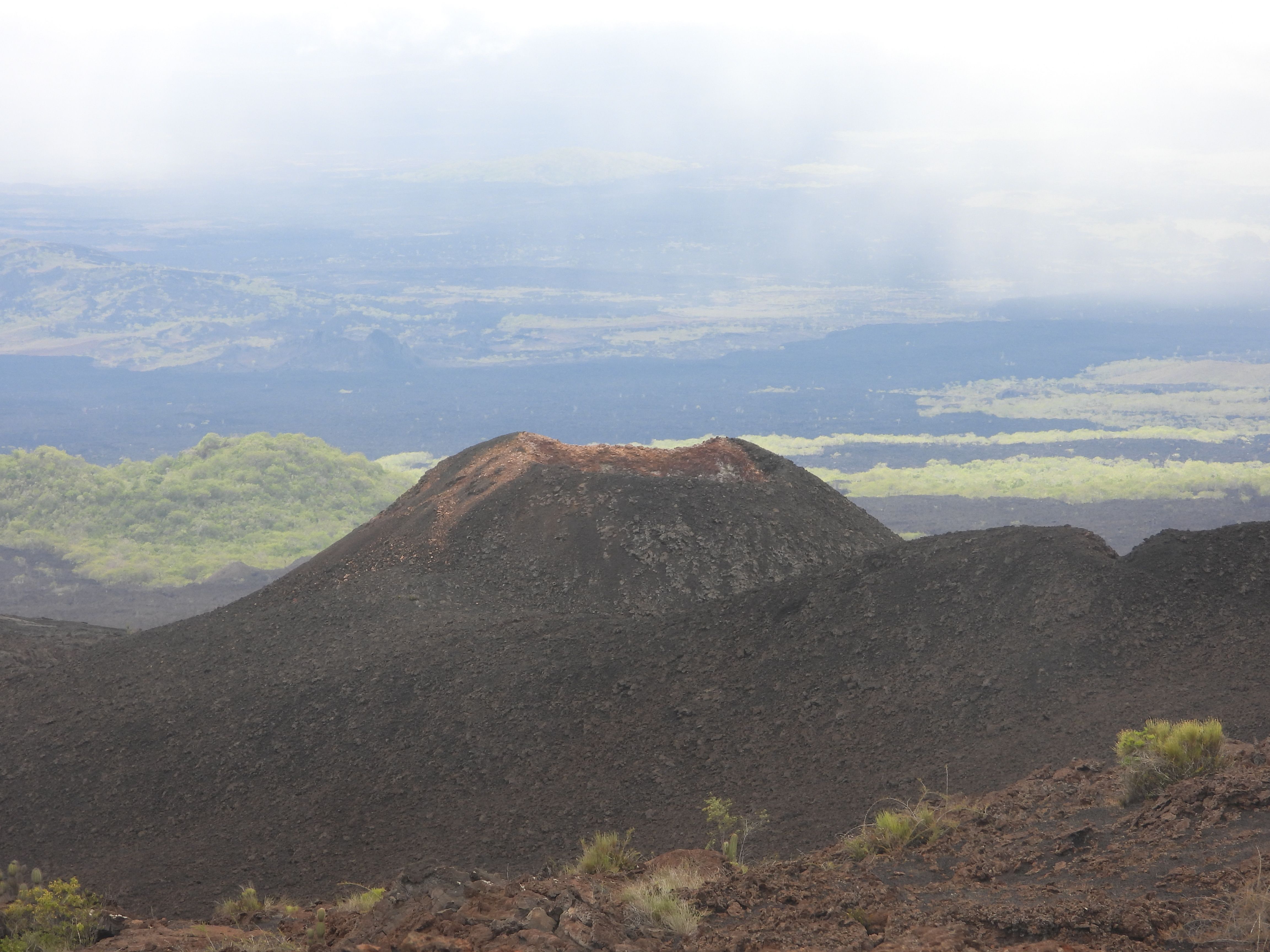 Volcán Chico, a parasitic cone on the northeastern flank of Sierra Negra Volcano, Isabela Island, Galápagos. This vent has erupted multiple times, most recently in 2005 and 2018, leaving fresh black lava fields and a reddish summit crater visible from the volcano’s rim trail.