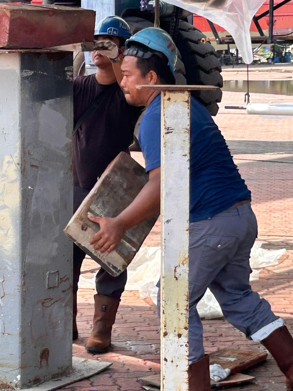 A boat worker carries heavy wood blocks at Lunas Shipyard.